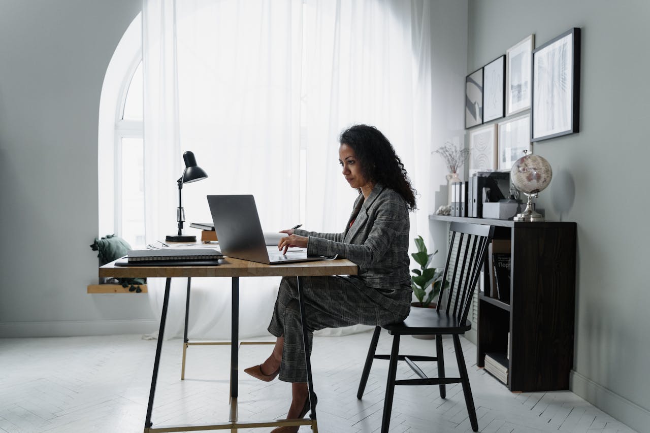 Business Management Best Practices for Growing Companies Businesswoman using a laptop at a stylish desk, focused on work in a modern office environment.